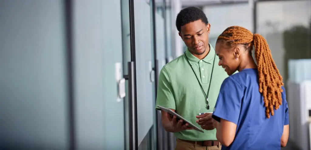Intelas team members reviewing information on a tablet in a bright, professional hallway setting.