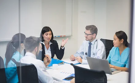 Intelas professionals, including clinical and administrative staff, engaged in a strategy meeting around a conference table in a modern office setting.