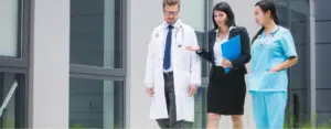 Doctor and nurses discussing patient information outside hospital building