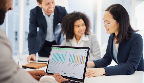 Intelas team members reviewing data visualizations on a laptop during a collaborative meeting in a bright office setting.