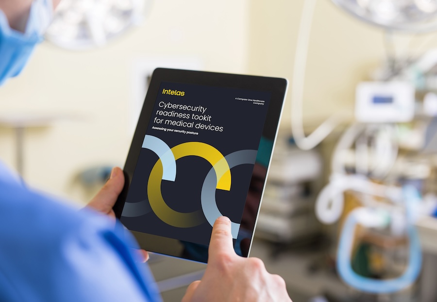 Healthcare professional holding a tablet displaying the Intelas 'Cybersecurity readiness toolkit for medical devices' in a clinical environment.